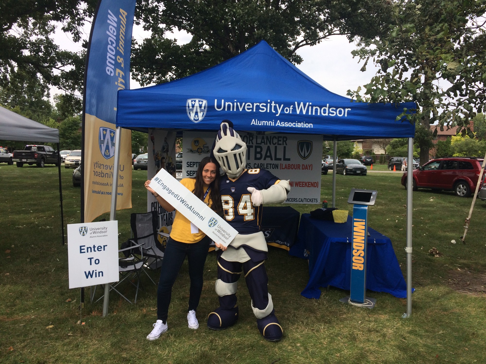Volunteer takes a photo with the Lancers mascot, Winston, at a community event.
