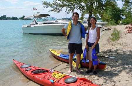 François Georges and Marie-Jeanne Monette standing on beach with kayaks.