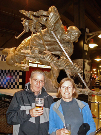 Gordon and Julie Joughin stand in front of a statue of the legendary Gordie Howe.