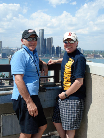 Alan Wright and Mark Schofield pose on the rooftop of a building with the Detroit skyline in the background.