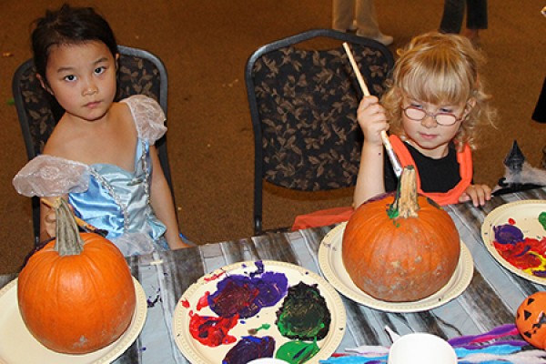 Kids in costume painting pumpkins