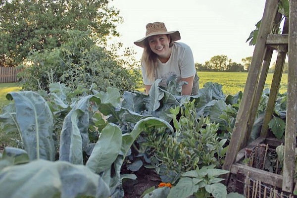 Brandi Bechard surrounded by a garden full of greens.