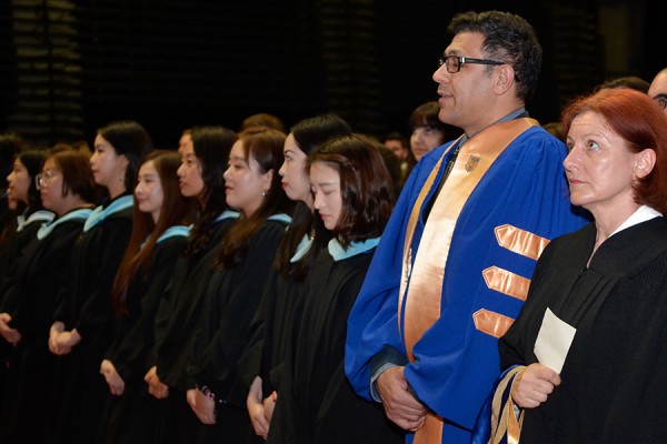 grads in gowns stand during Convocation
