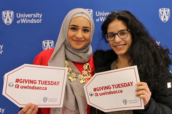 students holding Giving Tuesday signs