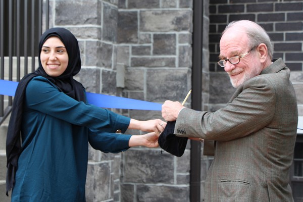 Summer Harb and Gordon Drake hold golden scissors to ornamental ribbon.