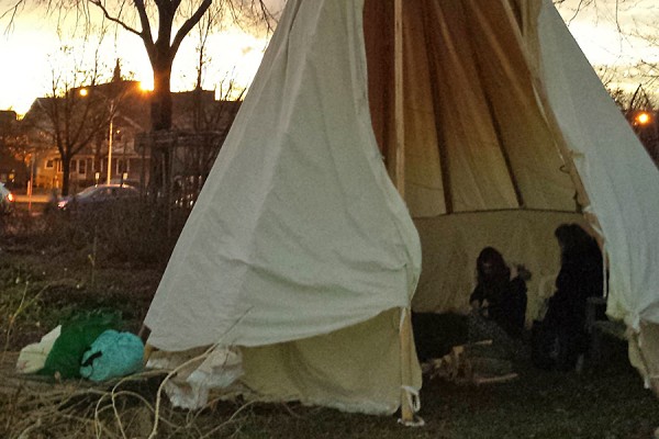 students in teepee in the Campus Community Garden