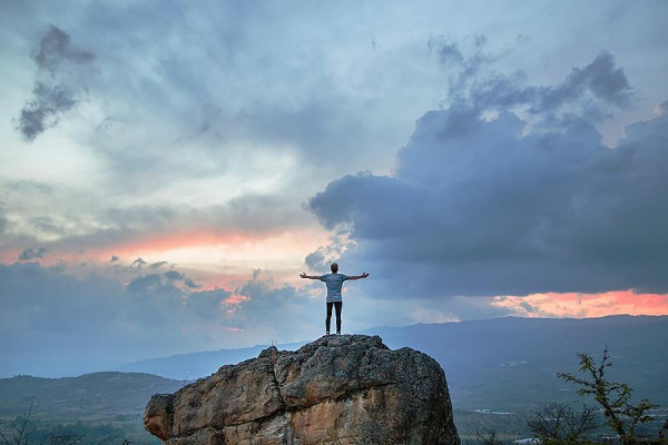 man standing on mountain before sunrise