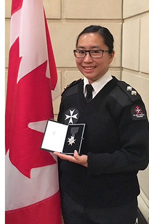 Tara Chan holding medal in front of Canadian flag