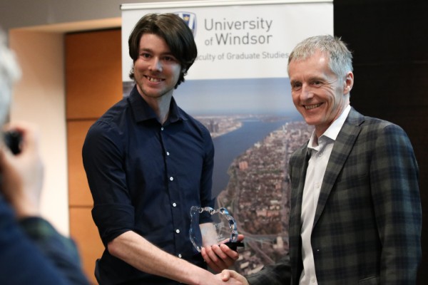 Ian Thomas, biological sciences master&#039;s student, accepts his award from University of Windsor President Alan Wildeman, during the Three Minute Thesis competition on Monday, March 26, 2018.