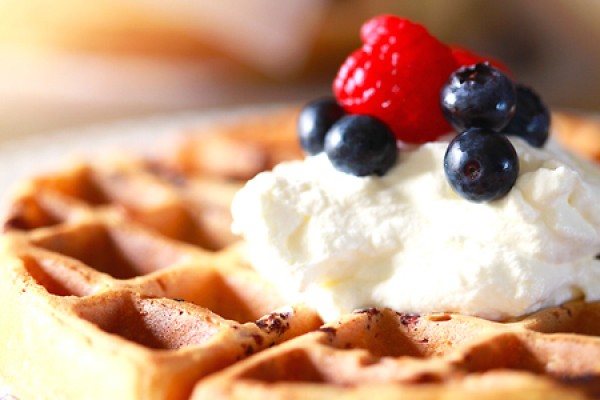 Belgian waffles toped with berries and whipped cream.