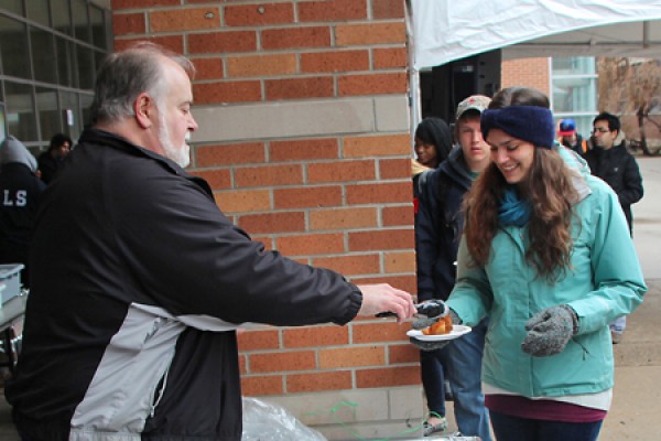 Staffer Dean Roy of IT Services gives a doughnut to a happy student.