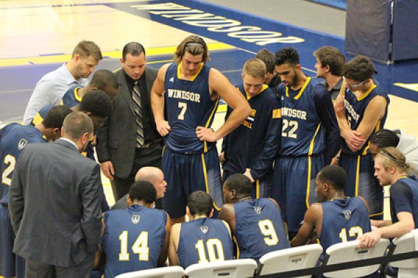 Lancer men&#039;s basketball players huddle by bench