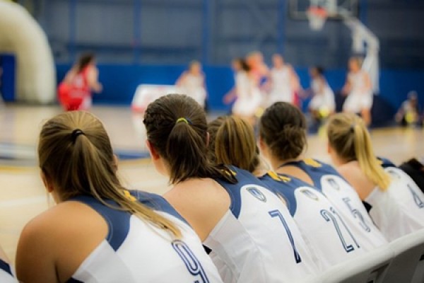 Lancer women&#039;s basketball players look onto the court from the bench.