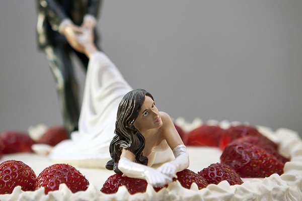 wedding cake topper depicting groom dragging reluctant bride
