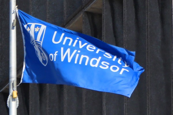 UWindsor flag on pole outside Chrysler Hall Tower