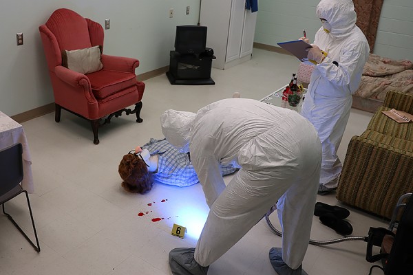 Forensic sciences students Stephanie Ringrose and Regan Pardo demonstrate investigative techniques in the mock crime scene condo.