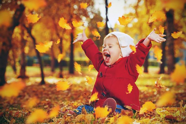 baby playing in pile of leaves