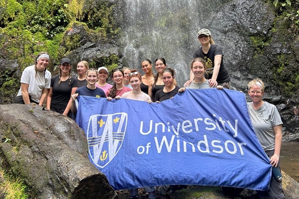 students and instructors pose by rainforest waterfall