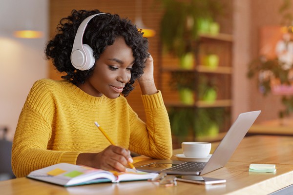young woman wearing headphones to work on laptop computer