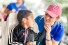 Melanie Renaud kneels next to young patient, newly outfitted with hearing aid