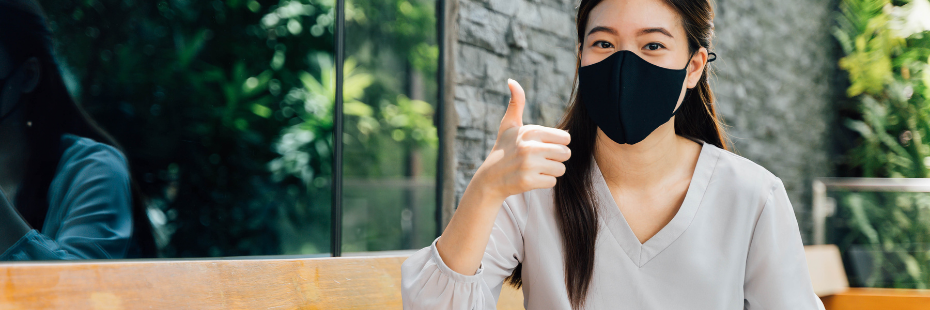 International female student with mask on raising one thumb up