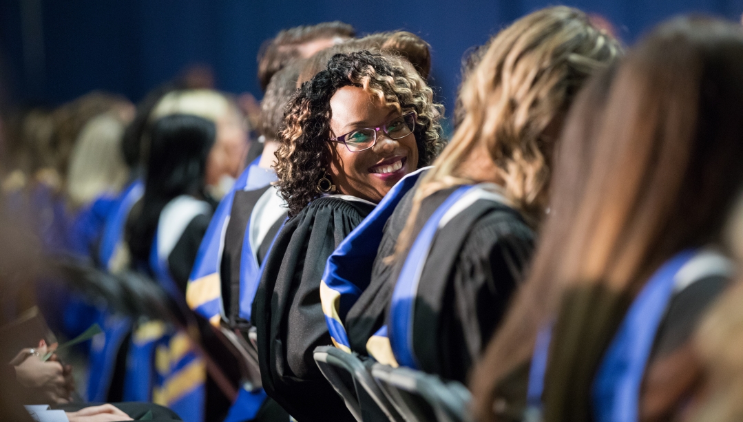 Female graduate looks back from seat and smiles