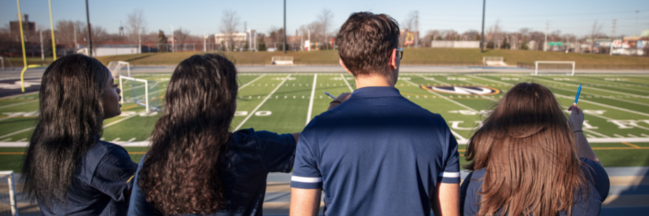 Four students overlooking football field