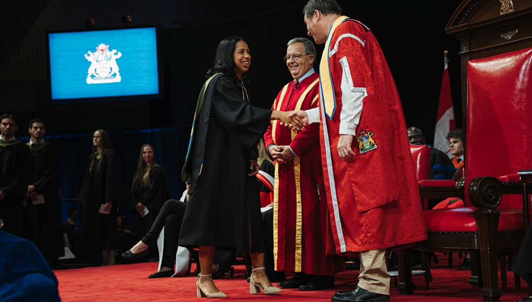 A graduating student is congratulated by Chancellor Dwight Duncan and President J.J. McMurtry.