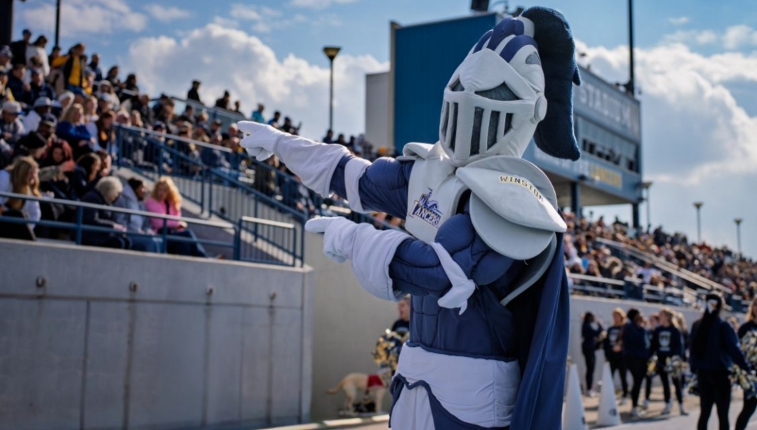UWindsor Lancer mascot Winston in front of a crowd at a football game