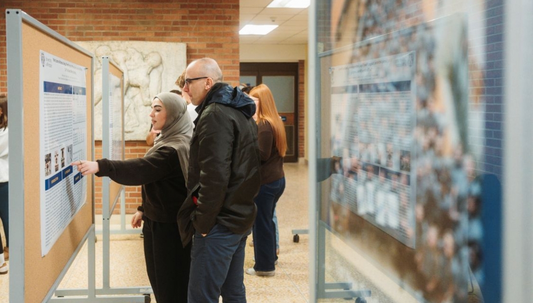 Two people look at a poster in a hallway
