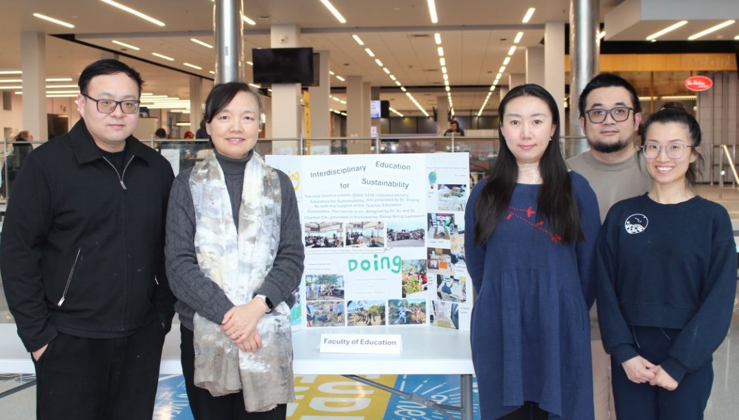 A group of people standing next to a poster board about sustainability in education