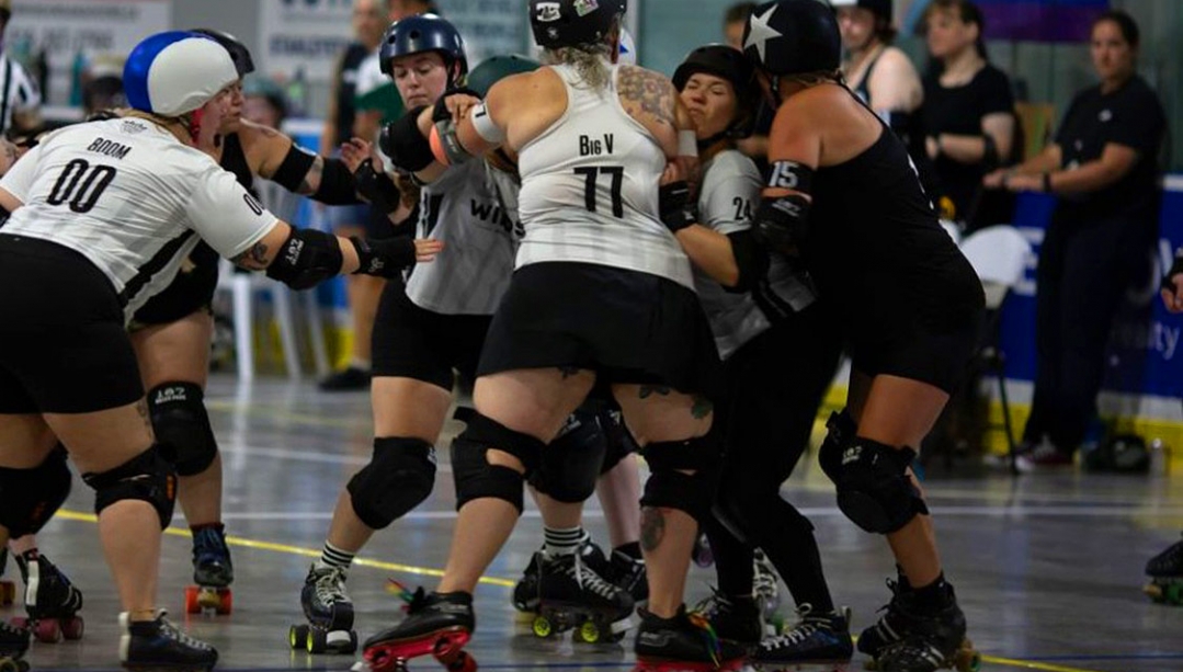 A wall of blockers in a roller derby game tries to stop their opponent