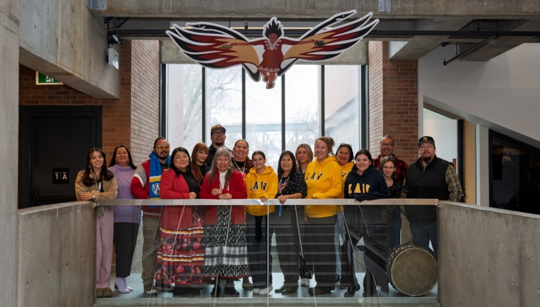A group of law faculty and staff stand beneath the Sky Woman art installation