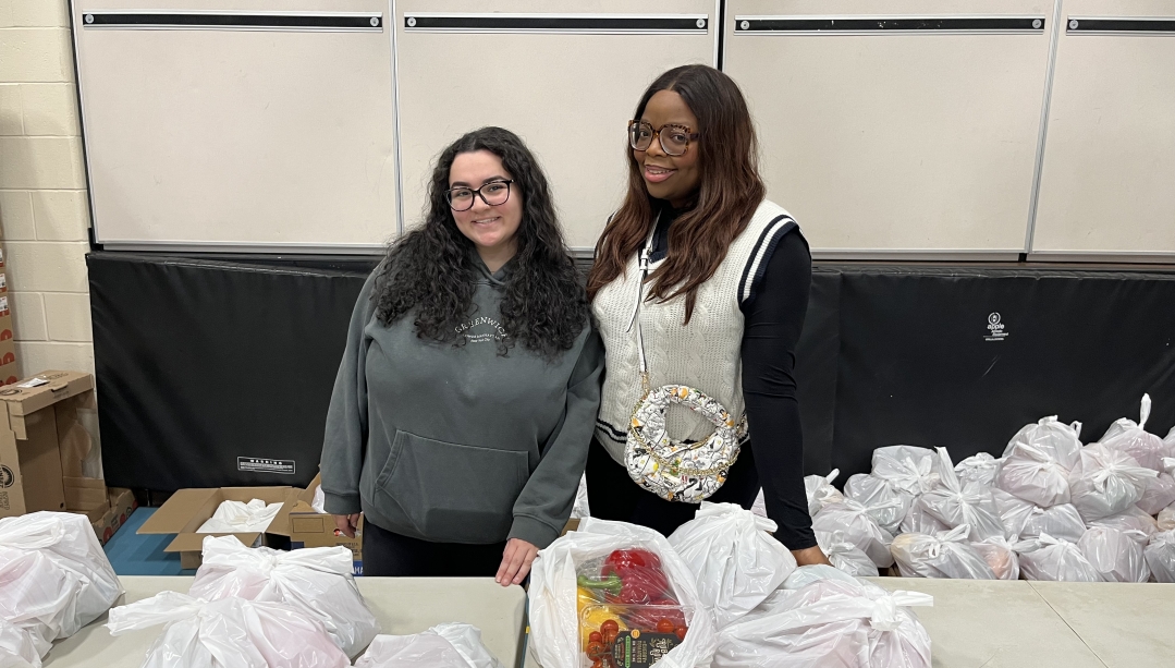 two students standing behind bags of produce