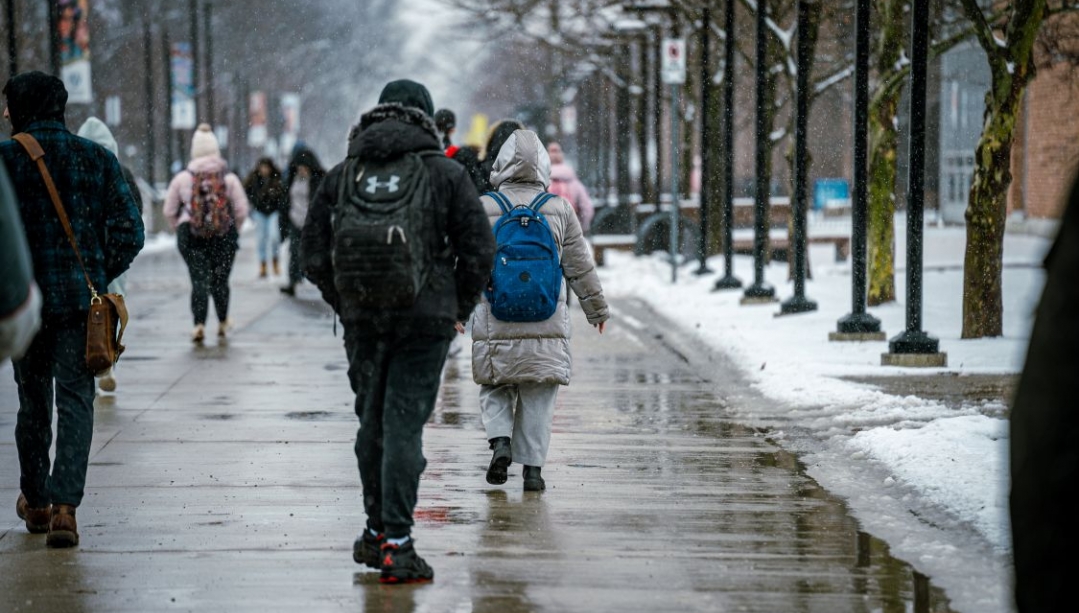students walk across the UWindsor campus on a snowy wet day