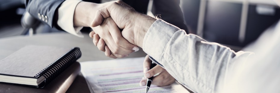 Two people shaking a hand over a filing a form