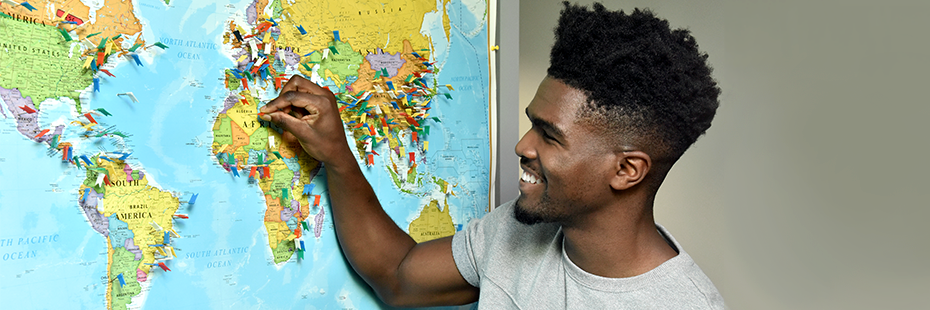 Student smiling and putting a pin onto a map located in the International Student Centre