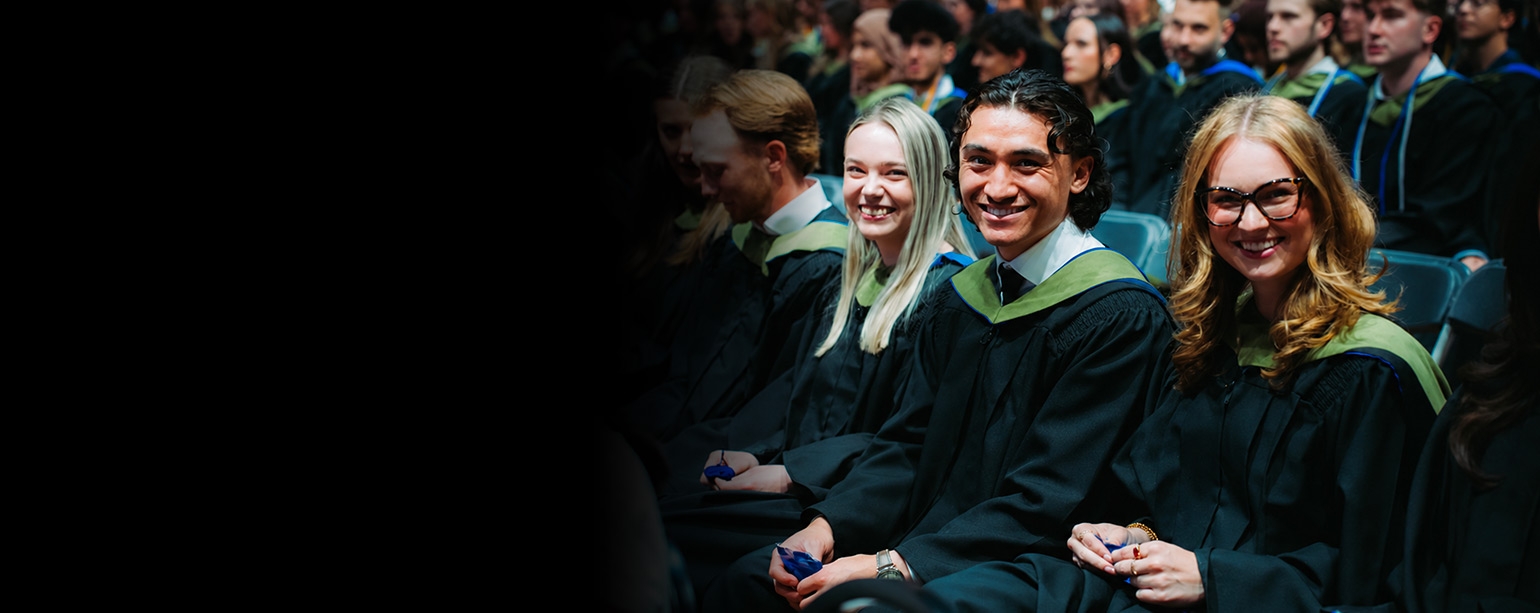 Two female and male graduands sitting at their seats waiting to go on stage