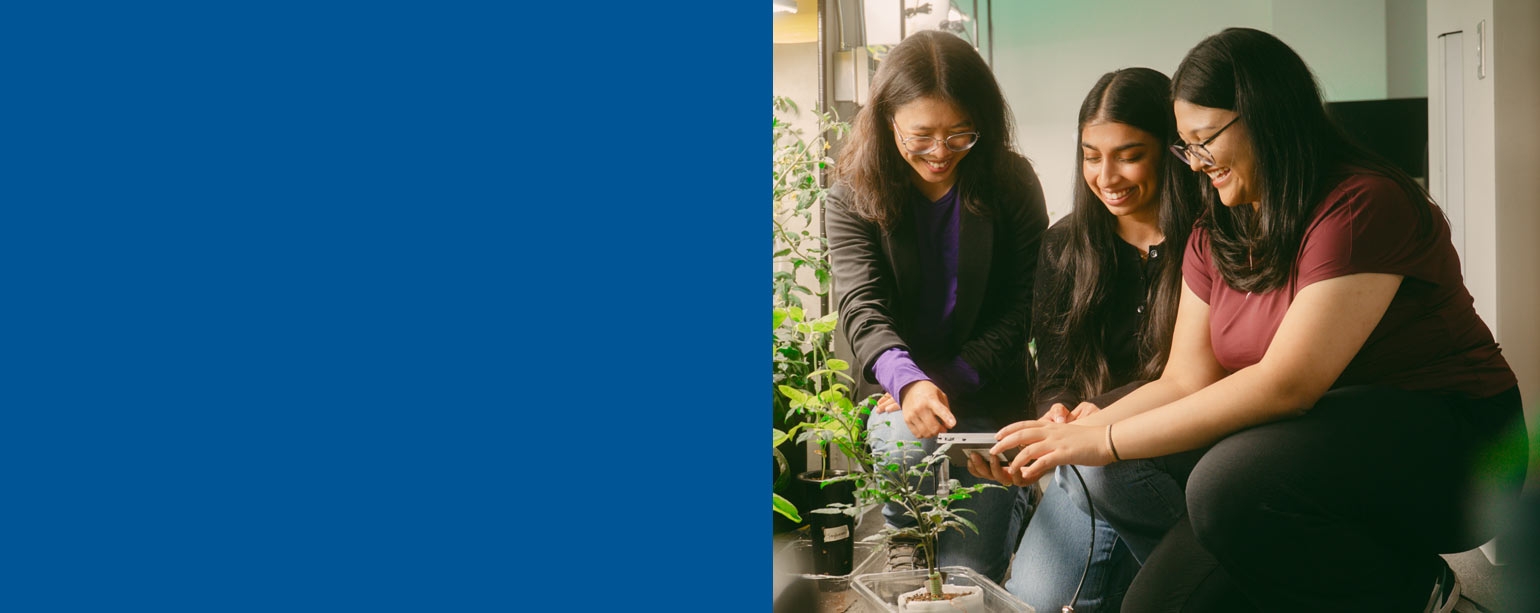 Female prof with two female students performing research on plants