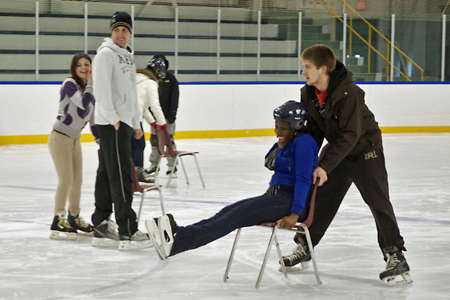 students sitting in chairs being pushed by students on skates