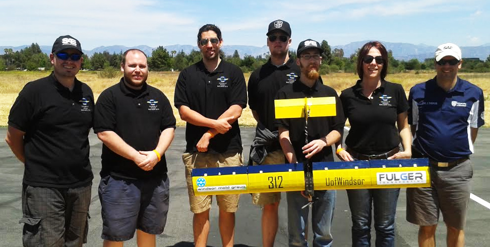 UWindsor team holding their successful aircraft deign at SAE Aero Design West Collegiate Competition. From left to right: Andrei Tineghe, Justin Abbott, Mitchell Campbell, David Carrick , Kevin Brooks, Richelle Dolan, and Faculty Advisor Jeff Defoe .
