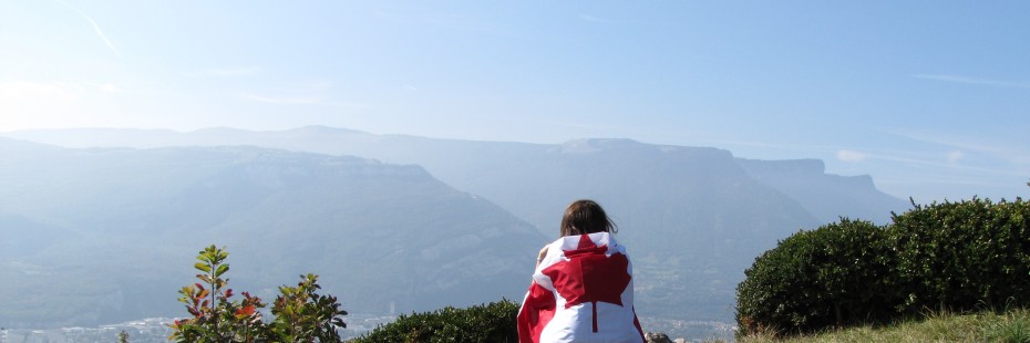 Exchange student sitting on a mountain with a Canadian flag