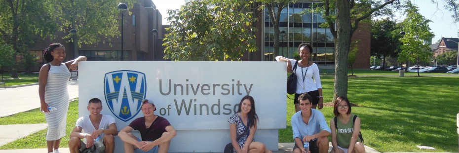 Group of students sitting in front of the UWindsor sign