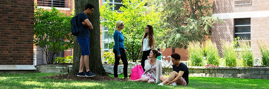 Students relax under a tree outside Dillon Hall