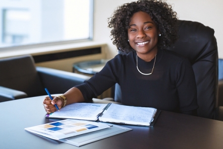 Student at desk with pen smiling. 