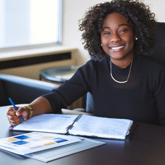 Student at desk with pen smiling. 