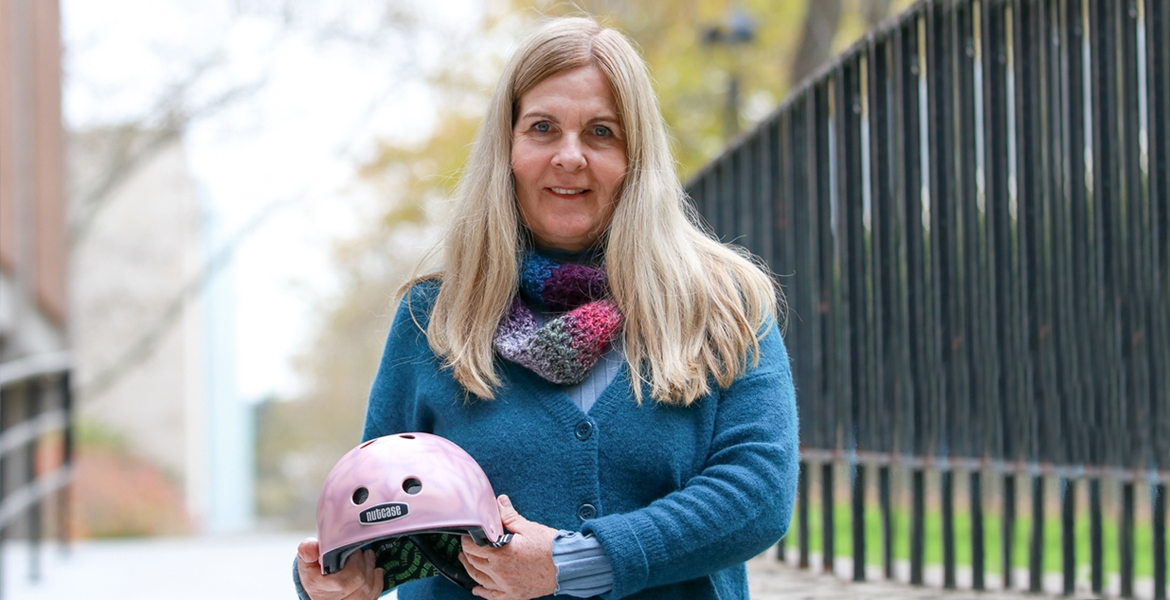 Professor Lori Buchanan holds a bicycle helmet, painted as part of the Brain Bucket research project of recent Master’s graduate Daniella Mlinarevic.