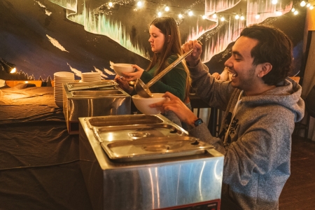 Two people serving themselves bowls of soup.