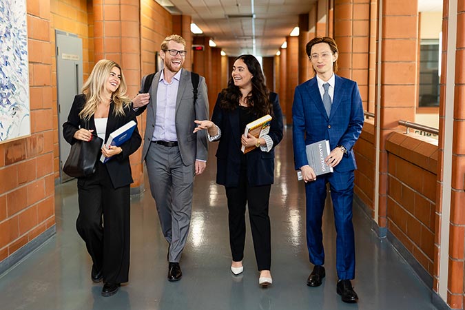 MBA students in business attire walking down a hallway