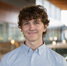 smiling young male with curly sandy hair and pale blue collared shirt